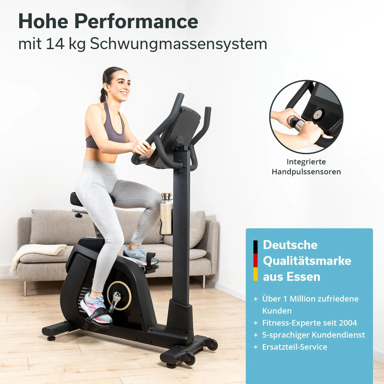 Fitnessbike mit 14 kg Schwungmasse. Person sitzt darauf, hält Lenker, graue Leggings, neben einem Sofa. Handpulssensoren sichtbar.