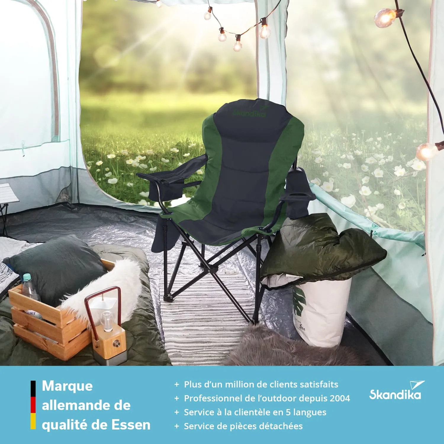 Campingstuhl in einem Zelt, von dem eine grüne Wiese mit Blumen sichtbar ist. Im Zelt sind Kissen und eine Holzbox.