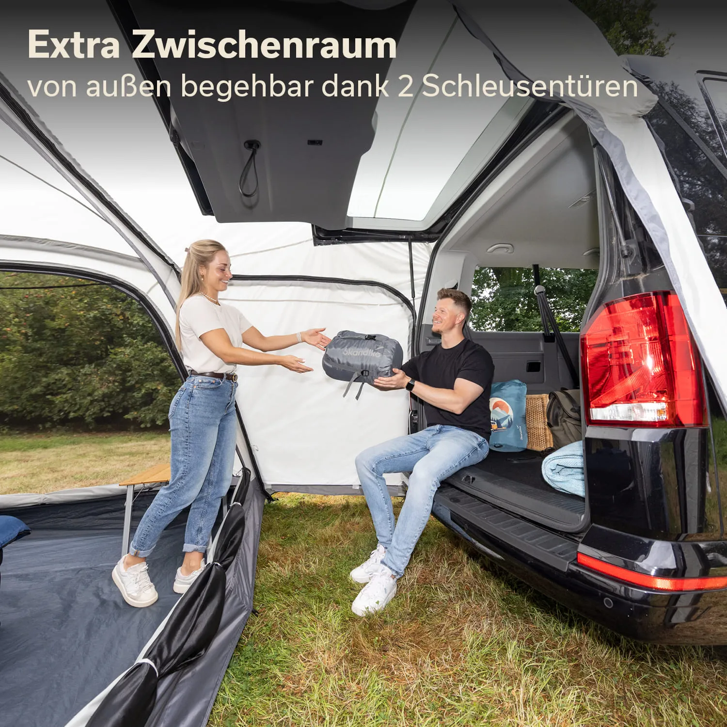 Zwei Personen stehen an einem Fahrzeug, während eine Person eine Tasche übergibt. Im Hintergrund ist ein Zelt erkennbar.