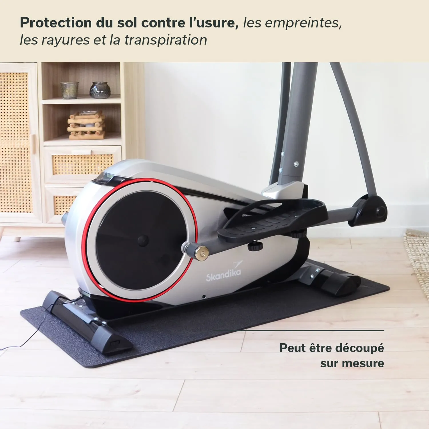 Elektromagnetisches Fitnessgerät mit einem schwarzen Fußpolster und grauem Gehäuse, platziert auf einem hellen Holzfußboden.