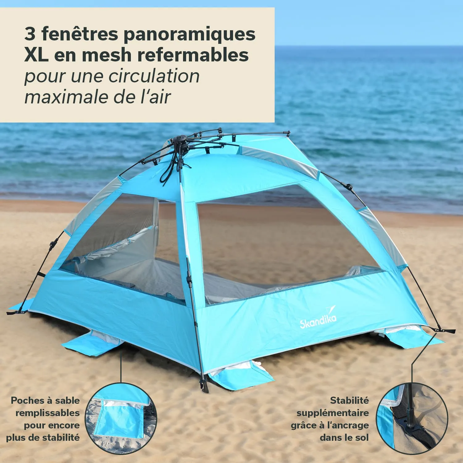 Zelt in Hellblau mit mesh Fenstern am Strand. Sand am Boden und Meer im Hintergrund. Stabilisierungsdetails sichtbar.
