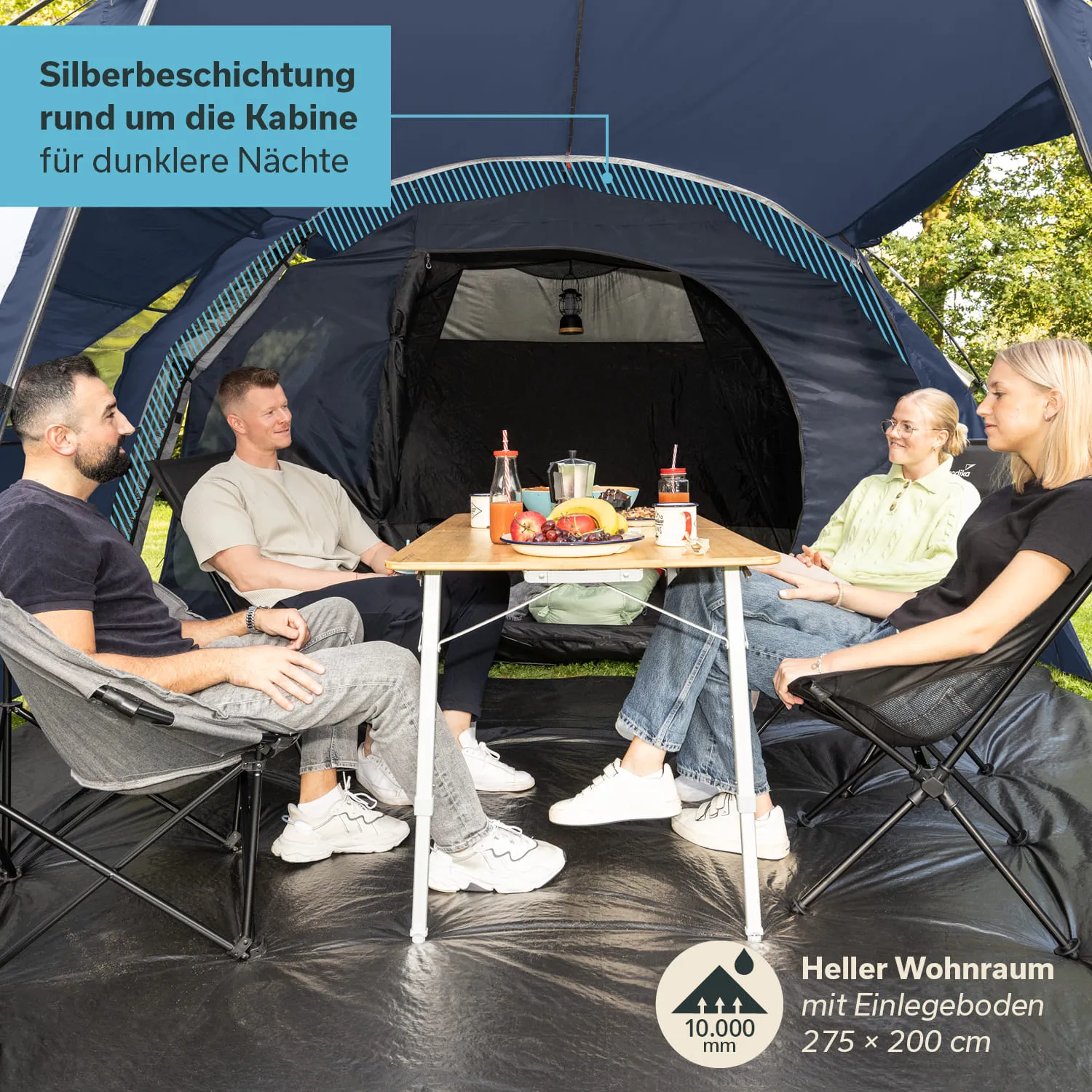 Im Zelt sitzen vier Personen um einen Tisch, auf dem Obst und Getränke stehen. Der Innenraum ist dunkel, mit einem hellen Boden.