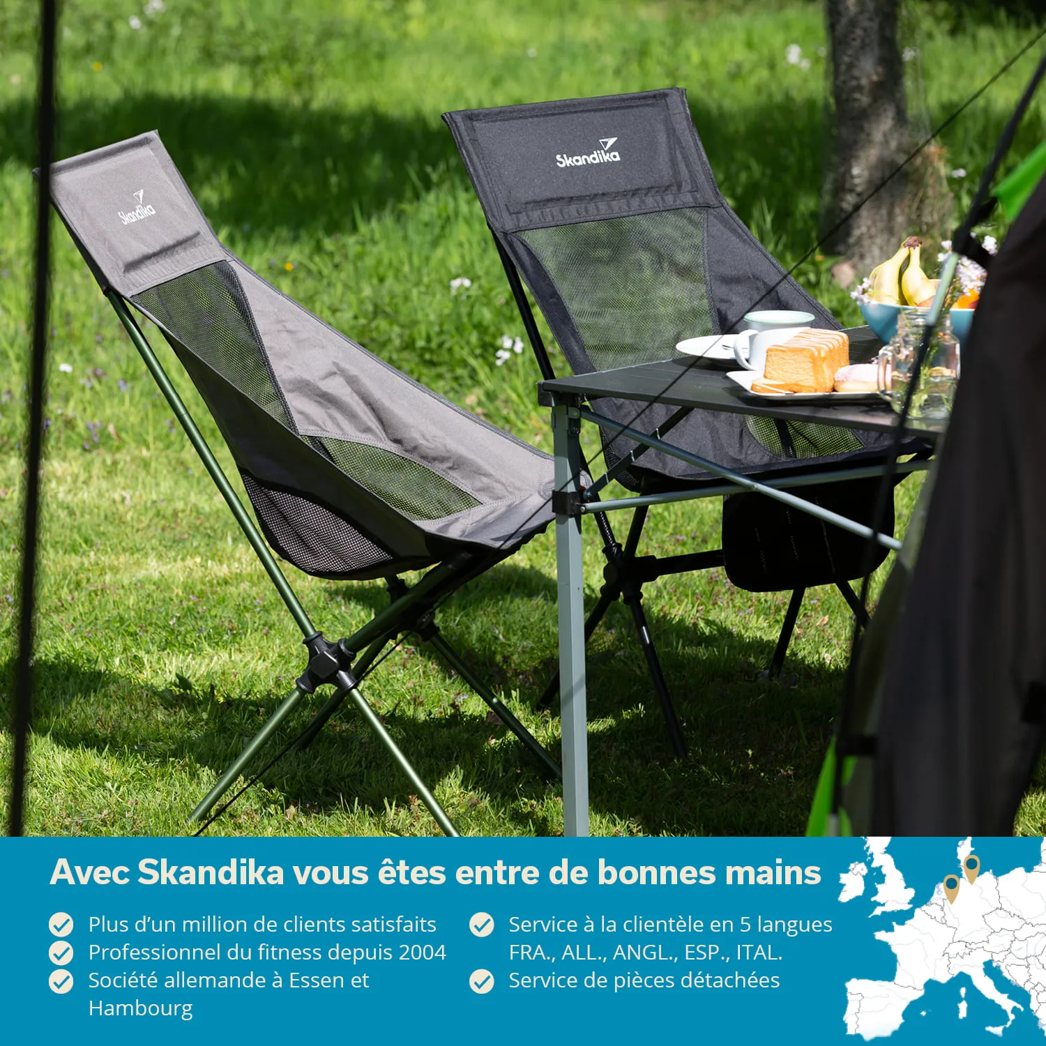 Zwei Campingstühle stehen nebeneinander auf einer grünen Wiese. Neben den Stühlen befindet sich ein klappbarer Tisch mit Geschirr und Essen.