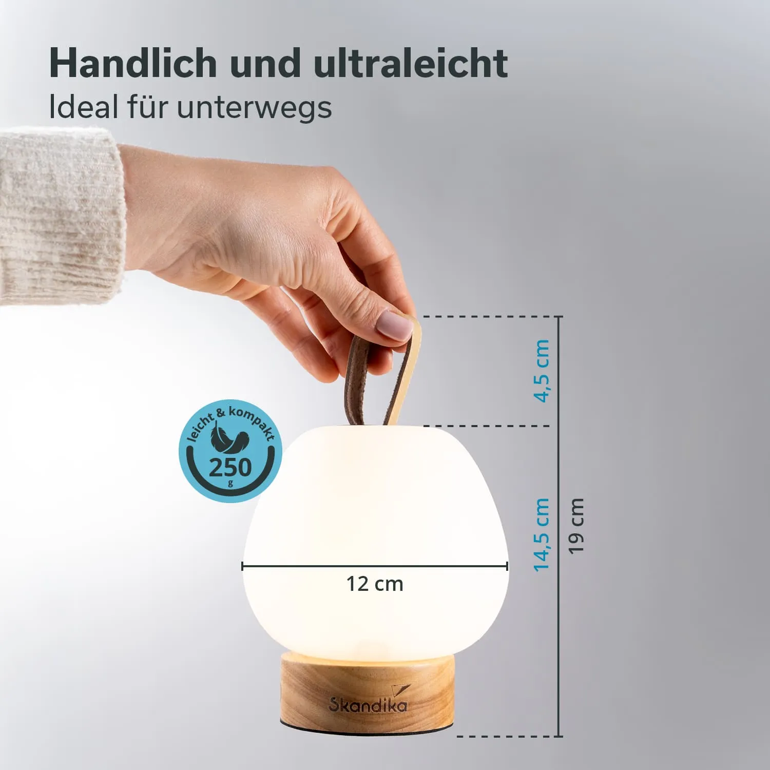 Eine handgehaltene, tragbare Lampe mit einem runden, weißen Lampenschirm und einem Holzfuß. Maße und Gewicht sind angegeben.