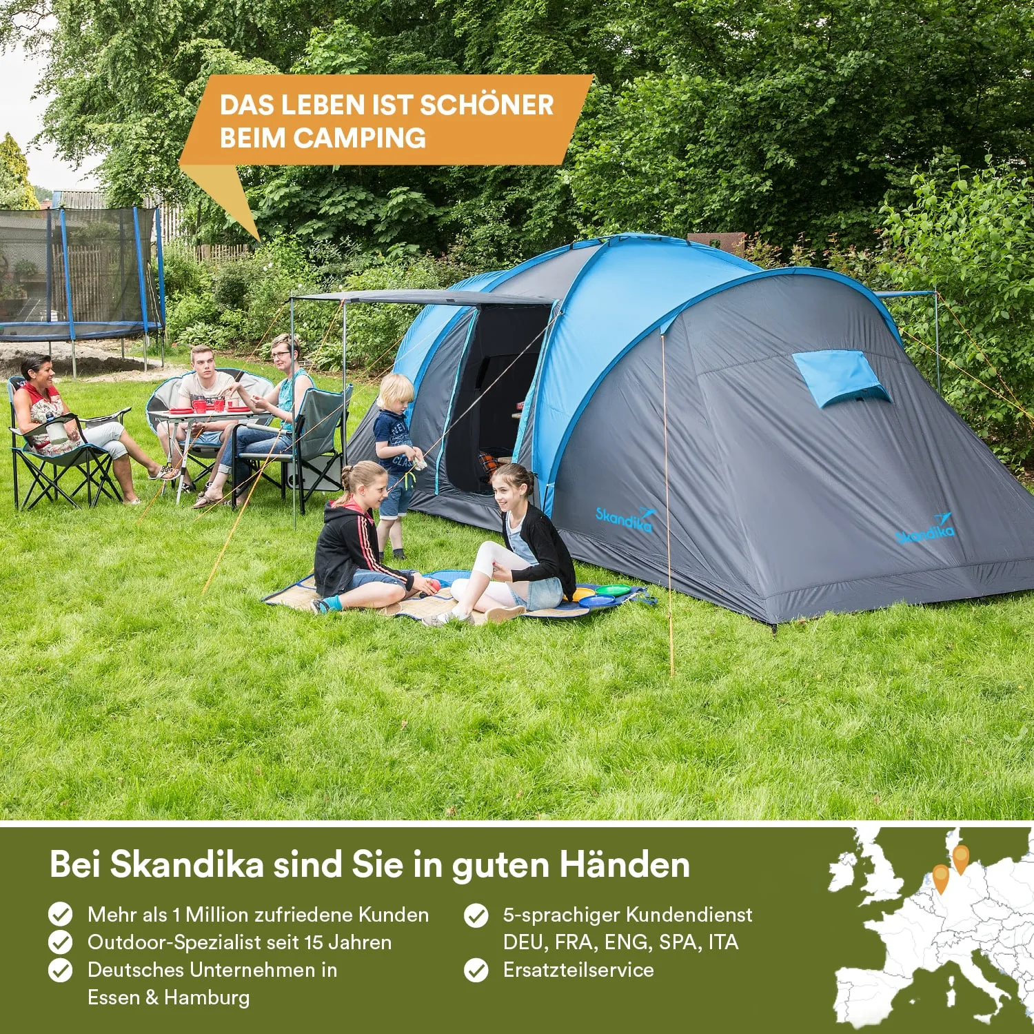 Zelt mit blauen und grauen Elementen auf einer grünen Wiese. Mehrere Personen sitzen auf Campingstühlen, spielen und essen.