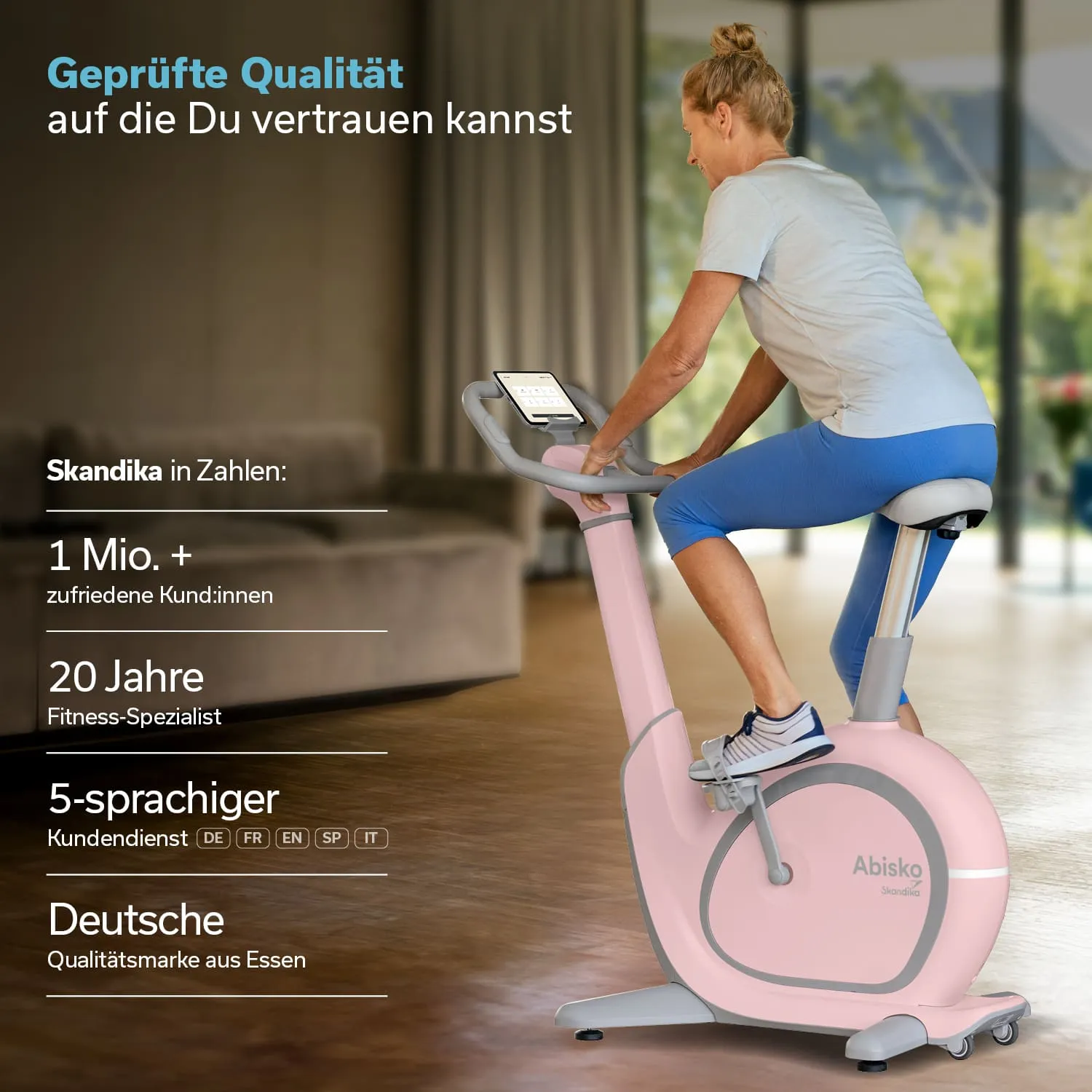 Stationäres Fahrrad in einem hellen Raum, genutzt von einer Person. Das Gerät ist pink und grau, mit einem digitalen Display.