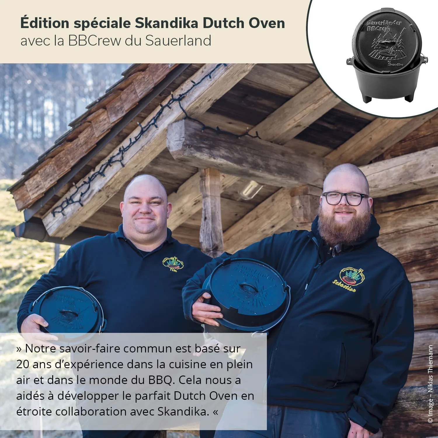 Zwei Personen halten Dutch Ovens vor einer rustikalen Holzstruktur. Die Landschaft im Hintergrund ist hügelig und bewaldet.