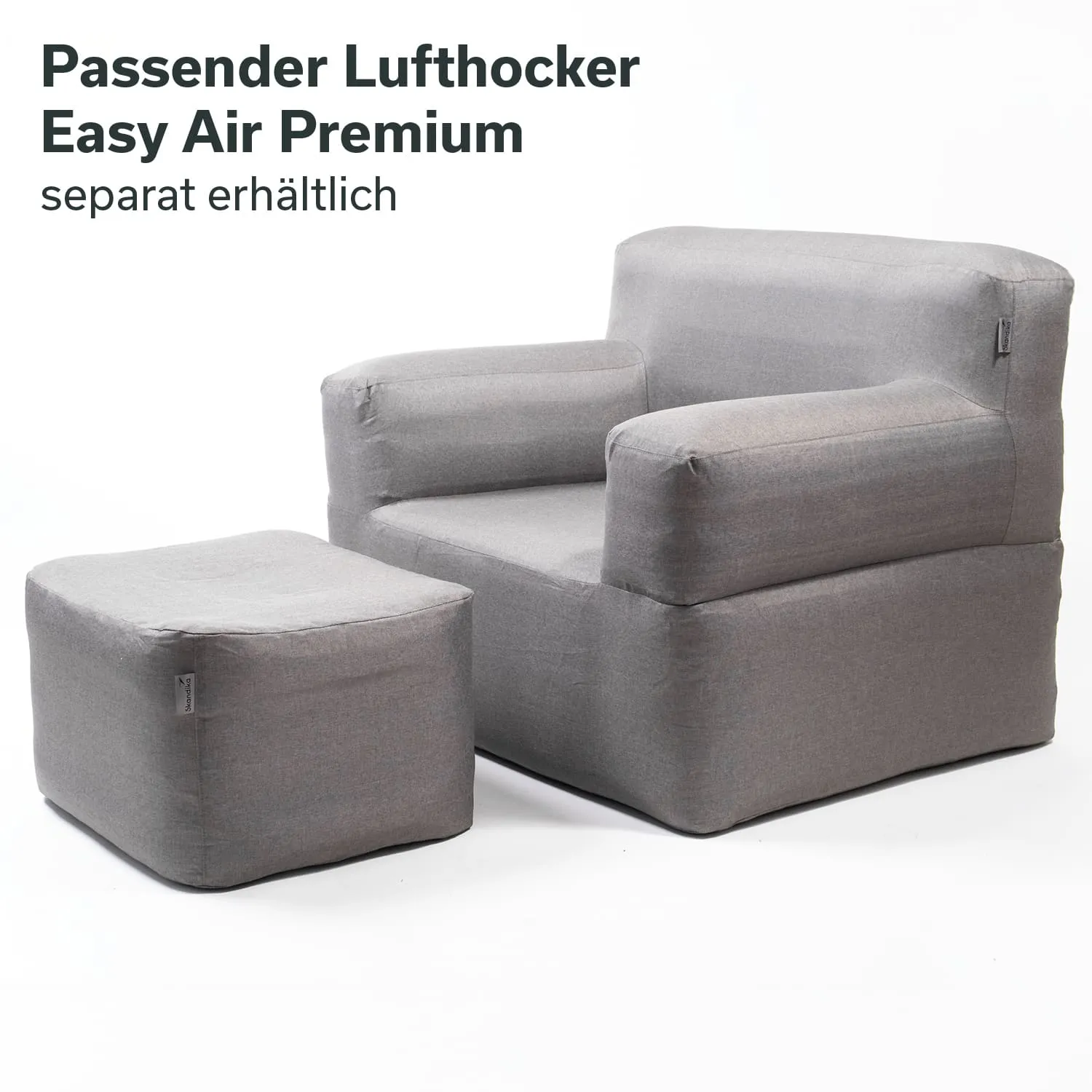 Grauer Sessel mit passenden Hocker, beide aus weichem Material, auf weißem Hintergrund.