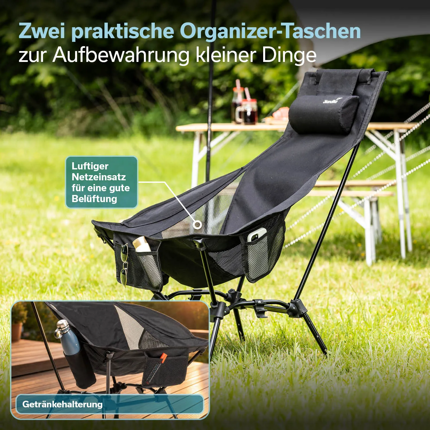 Schwarzer Klappstuhl mit breiter Sitzfläche und abnehmbarem Kissen, daneben ein Picknickkorb auf einem Teppich im Gras.