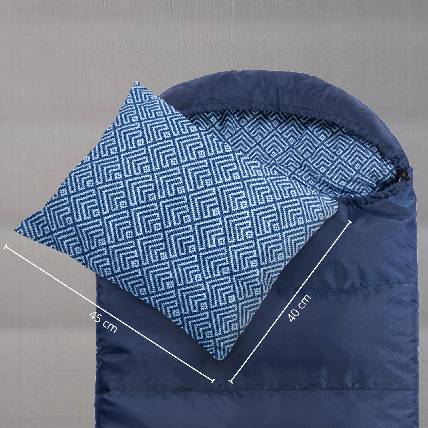 Blaue Schlafsacköffnung mit einem Kissen in geometrischem Muster. Maße: Kissen 45 cm, Schlafsack 40 cm breit.