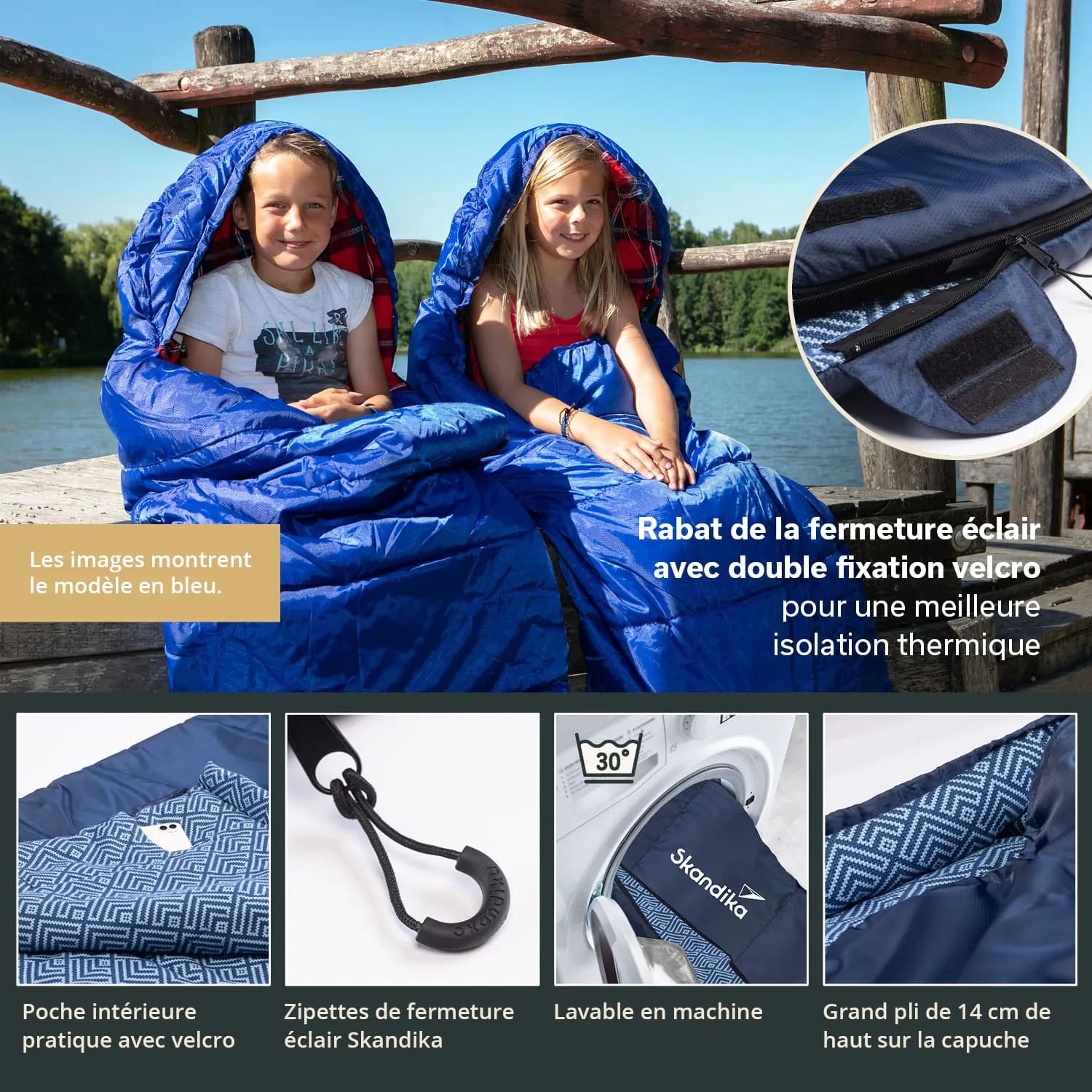 Zwei Personen sitzen an einem Steg am Wasser, eingewickelt in blaue Schlafsäcke. Der Hintergrund zeigt Bäume und Wasser.