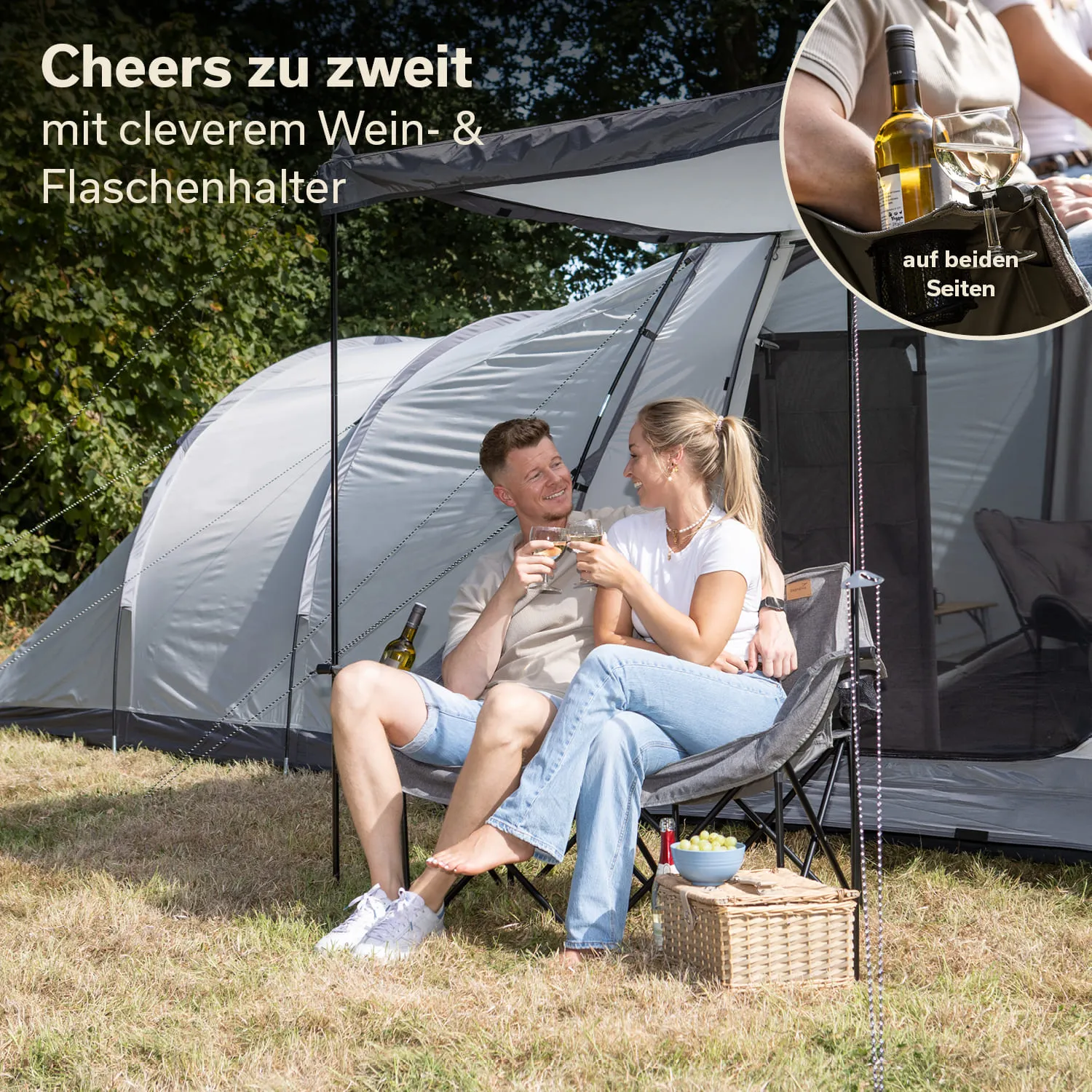 Paar sitzt in Faltstühlen vor einem Zelt, hält Gläser mit Getränken. Neben ihnen stehen ein Weinkühler und eine Box mit Snacks.