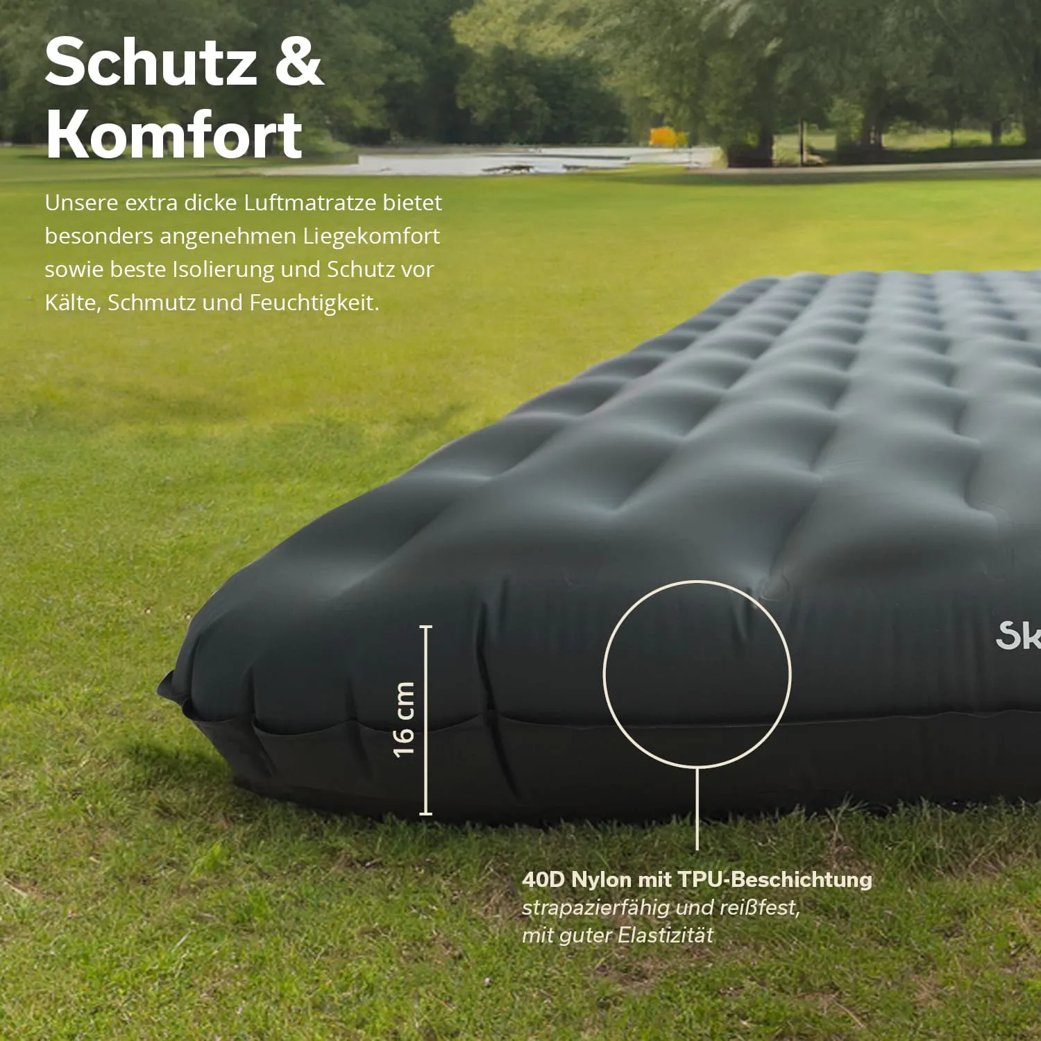 Schwarze Luftmatratze auf grünem Rasen, mit Maßangabe von 16 cm Höhe. Hintergrund: Wald mit Wasserfläche.