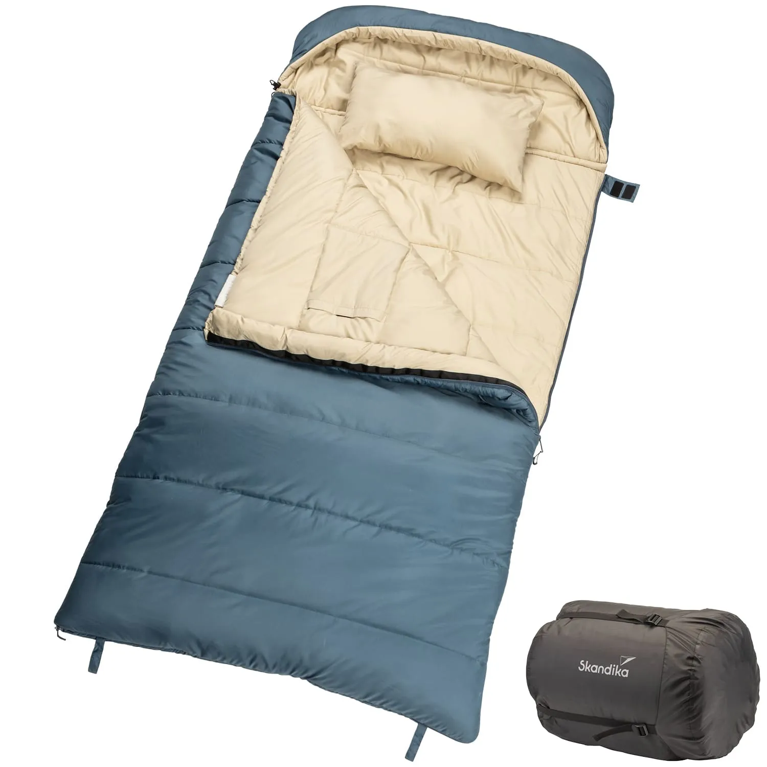Blaue Schlafsack mit beige-farbenem Innenfutter und Kissen. Rechts daneben ein komprimierter Schlafsack in schwarzer Tasche.