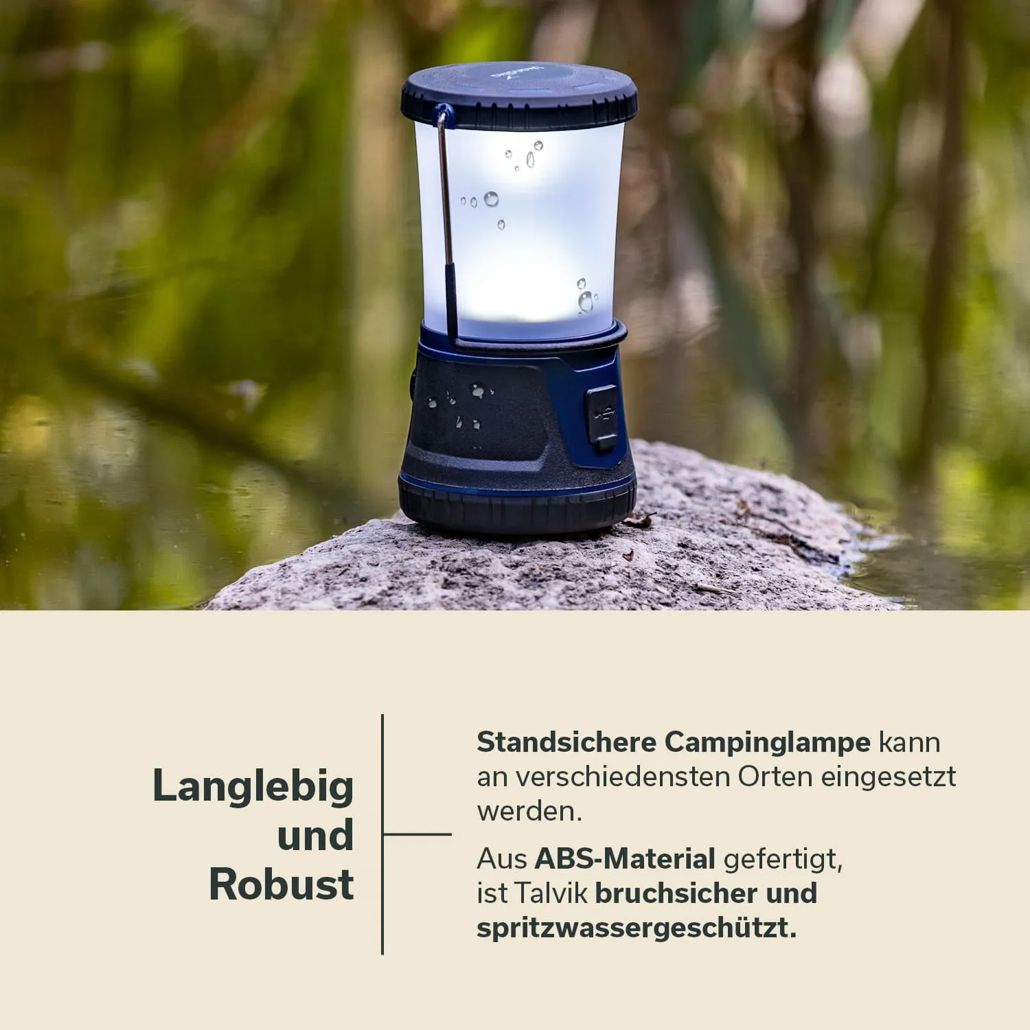 Campinglampe auf einem Stein, im Hintergrund reflektierendes Wasser und grünes Ufer. Lampe hat einen transparenten Behälter und einen schwarzen Sockel.