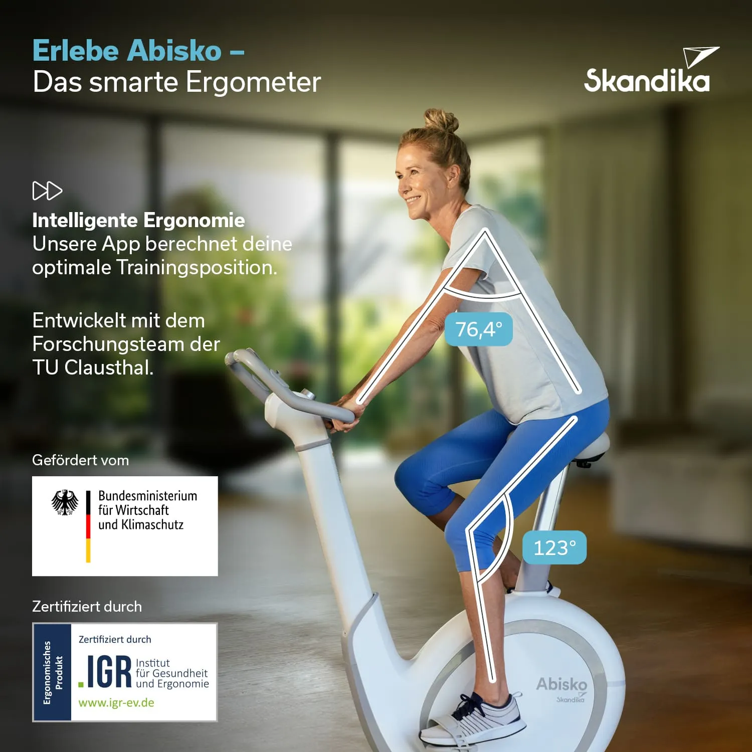 Ergometer mit einer Person, die darauf sitzt, in einem hellen Raum mit Pflanzen im Hintergrund. Text über das Produkt.