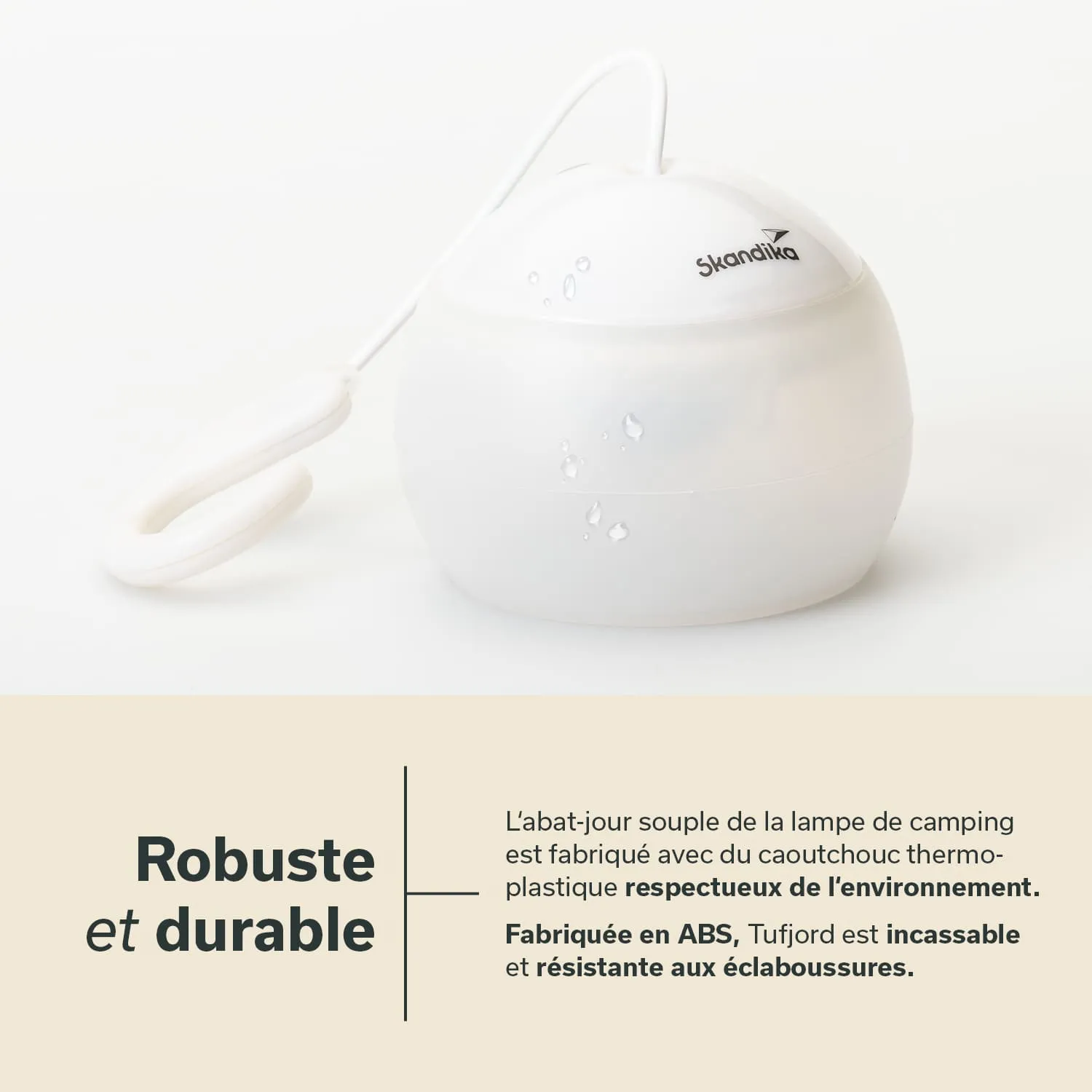 Kleine, runde Lampe mit weißem, mattem Gehäuse und Öse zum Aufhängen. Wassertröpfchen auf der Oberfläche.