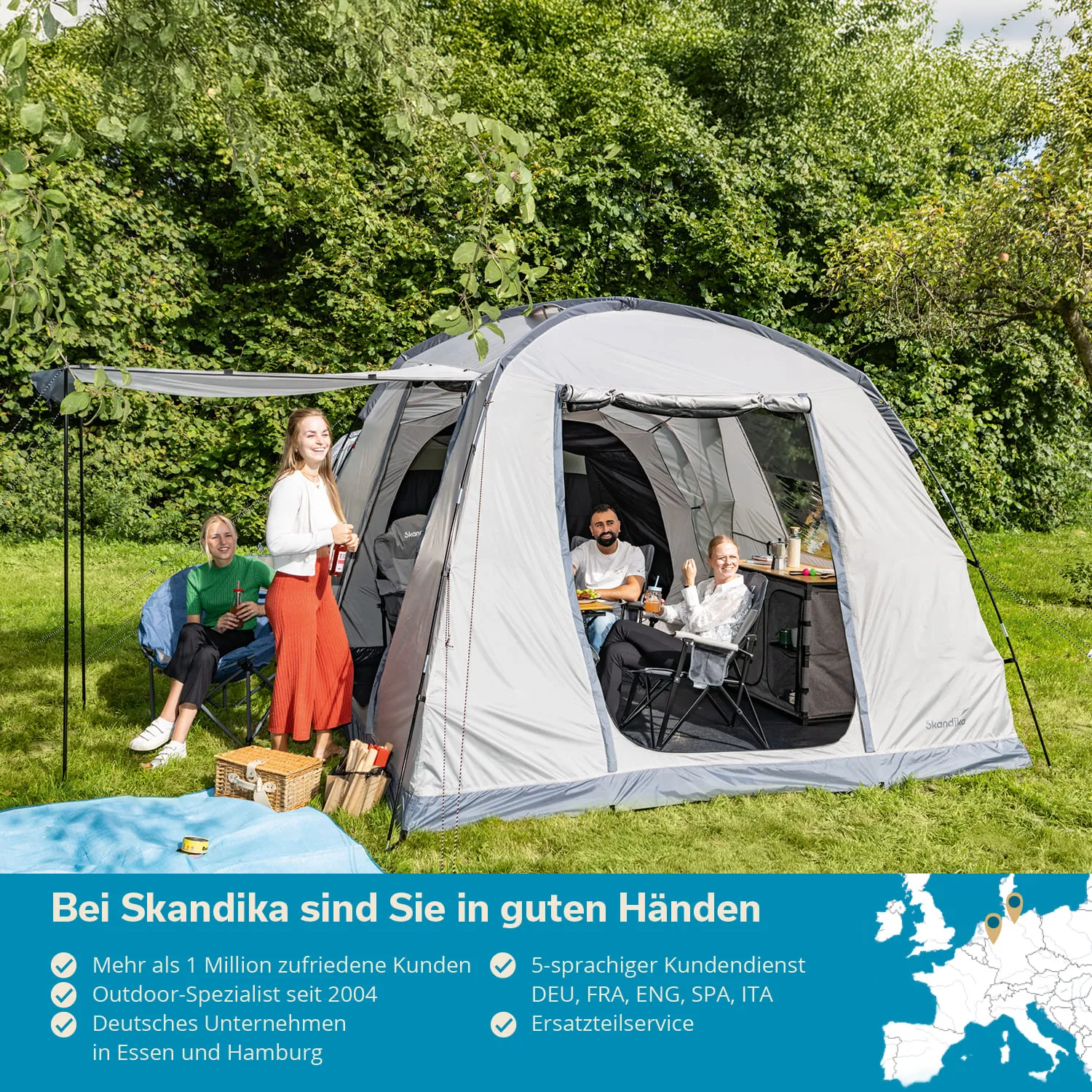 Graues Zelt im Freien, umgeben von Bäumen. Vier Personen sitzen auf Campingstühlen und genießen Getränke.
