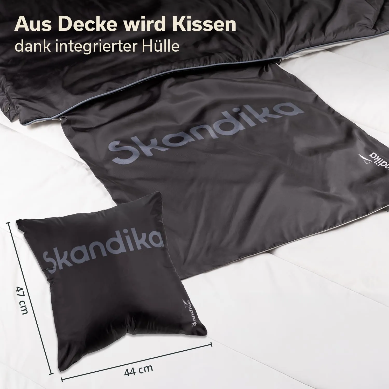 Schwarze Decke mit integriertem Kissen, beide mit dem Schriftzug "Skandika", liegen auf einer hellen Unterlage.