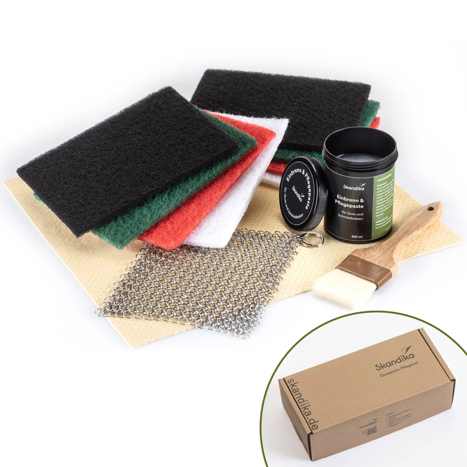 Reinigungs- und Pflegeutensilien: vier Scheuerschwämme in verschiedenen Farben, eine Dose Pflegepaste, eine Bürste und eine Metallkette.