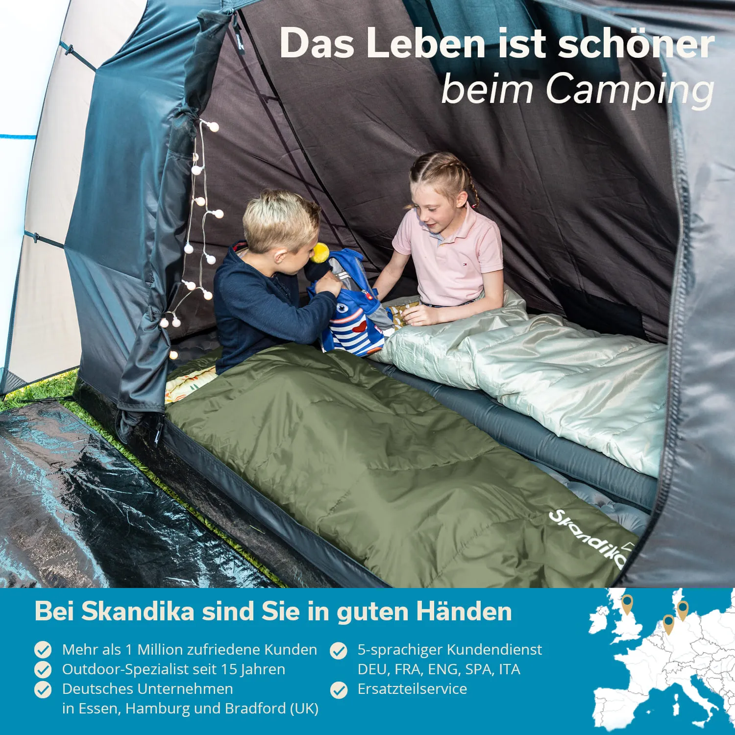 Zelt mit zwei Kindern in Schlafsäcken. Ein Kind hält ein Spielzeug, das andere sitzt daneben. Lichterkette im Zelt.