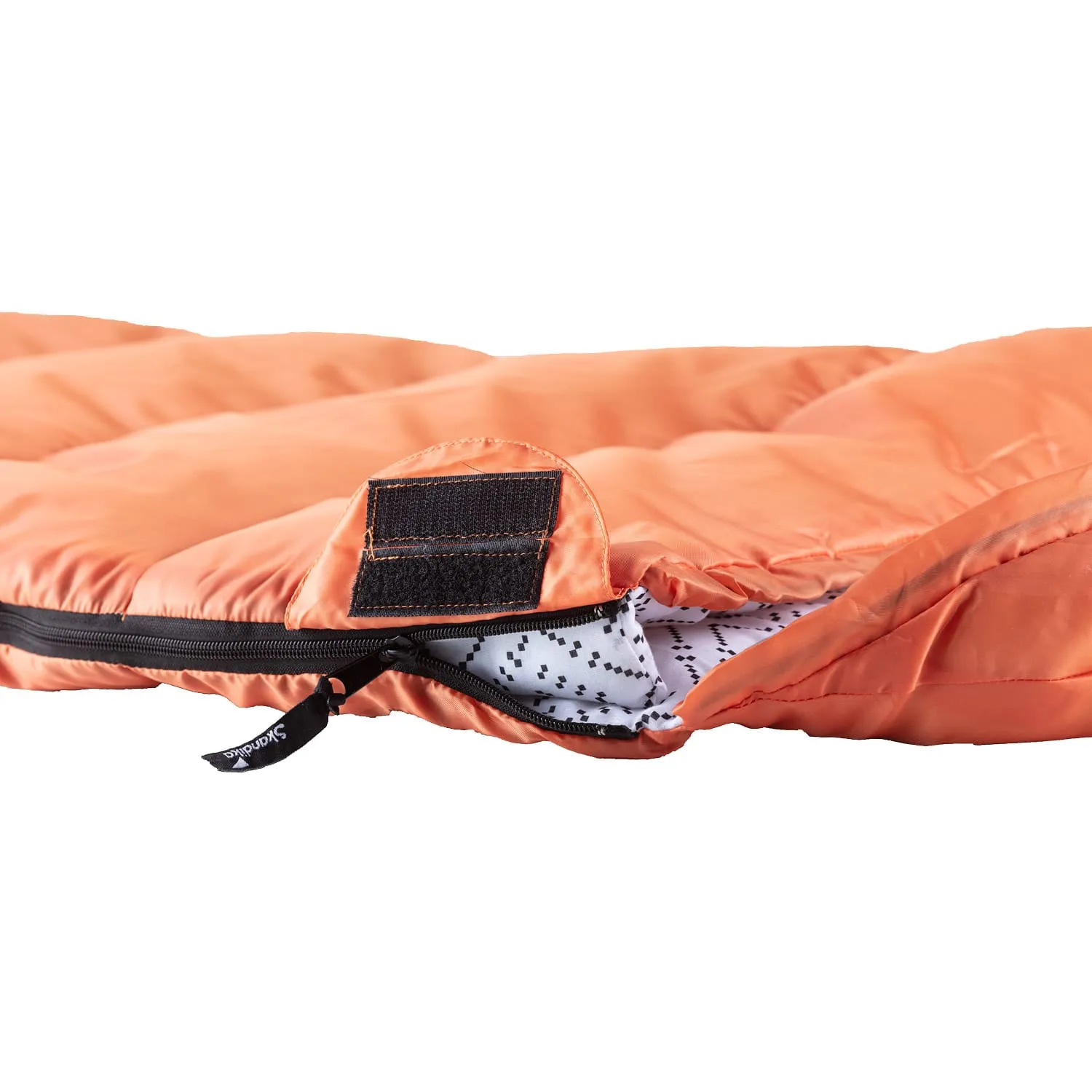 Ein orangefarbener Schlafsack mit Reißverschluss und einem inneren Stoff in Weiß mit schwarzem Punktmuster.