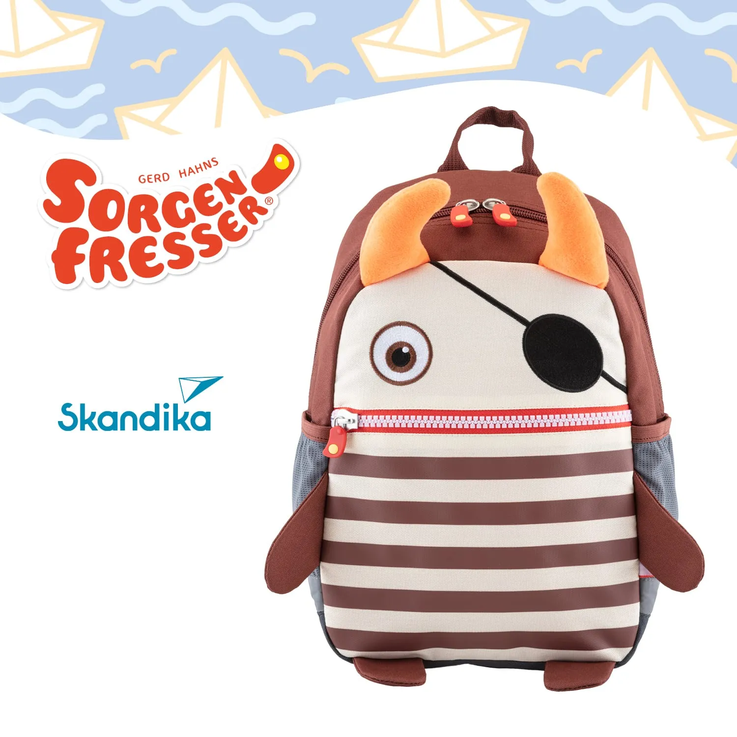 Ein Rucksack in Form eines Monsters mit Augen, einem Piratenaugenklappe und Hörnern. Der Rucksack hat gestreifte Elemente und eine kleine Tasche.