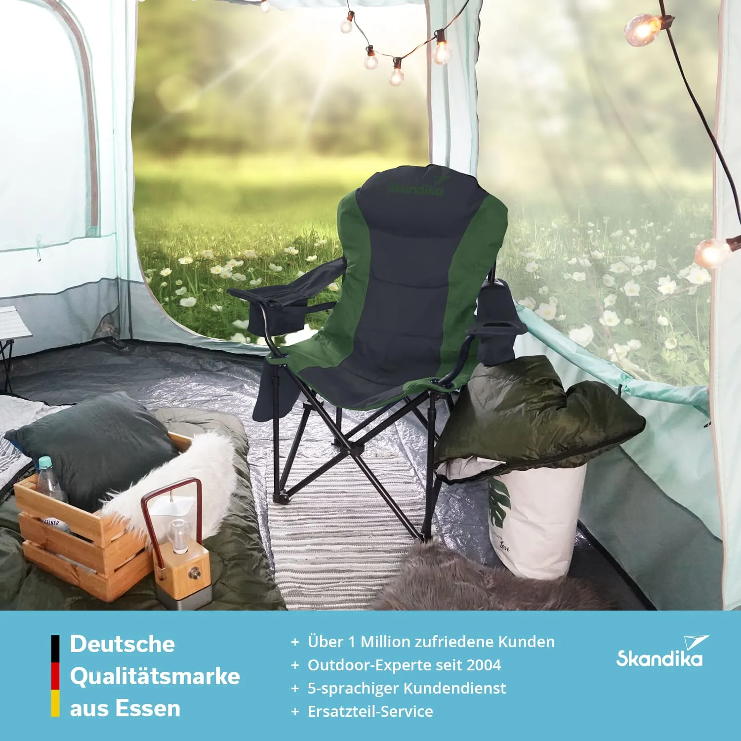Campingstuhl in einem Zelt, umgeben von Kissen, einer Holzbox und einer Flasche. Im Hintergrund eine grüne Wiese.
