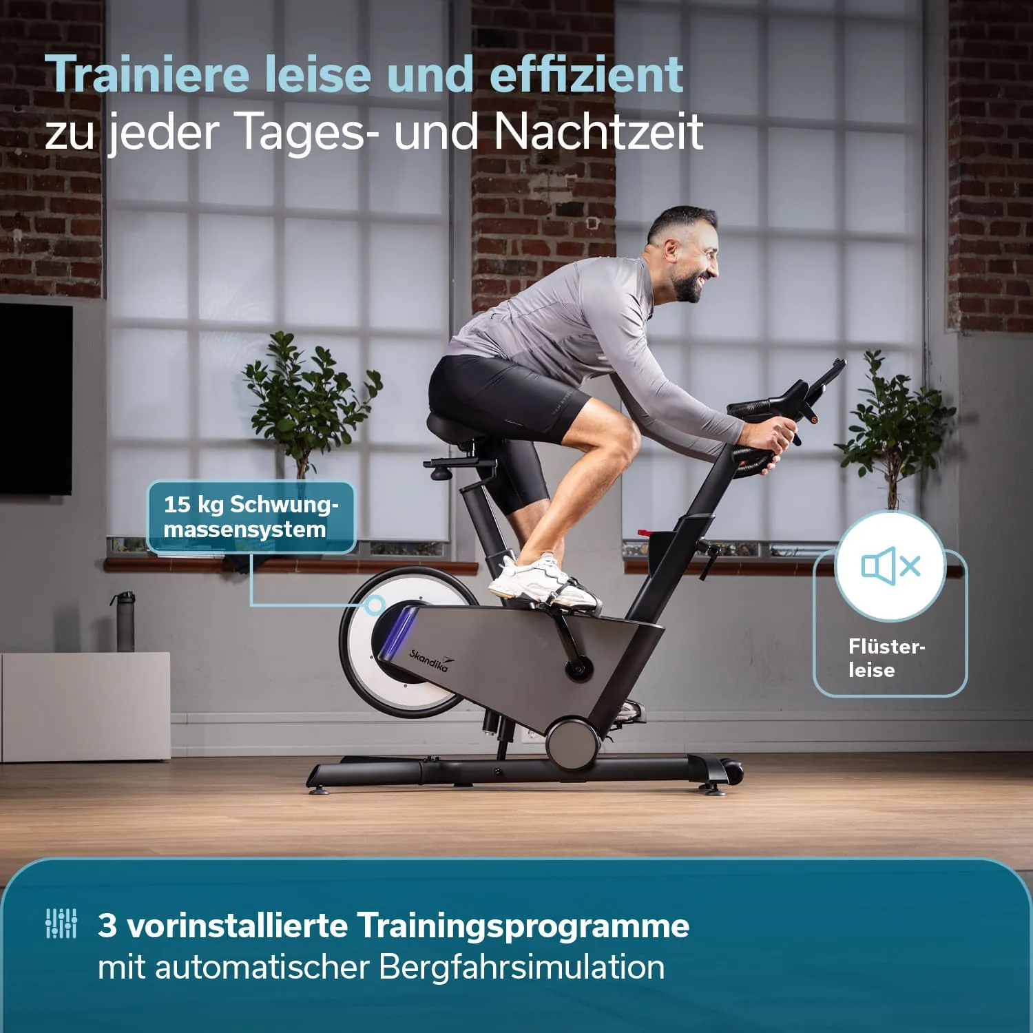 Ein Heimtrainer steht in einem Raum. Eine Person sitzt auf dem Fahrrad und trainiert. Hinter der Person sind große Fenster und eine Pflanze zu sehen.