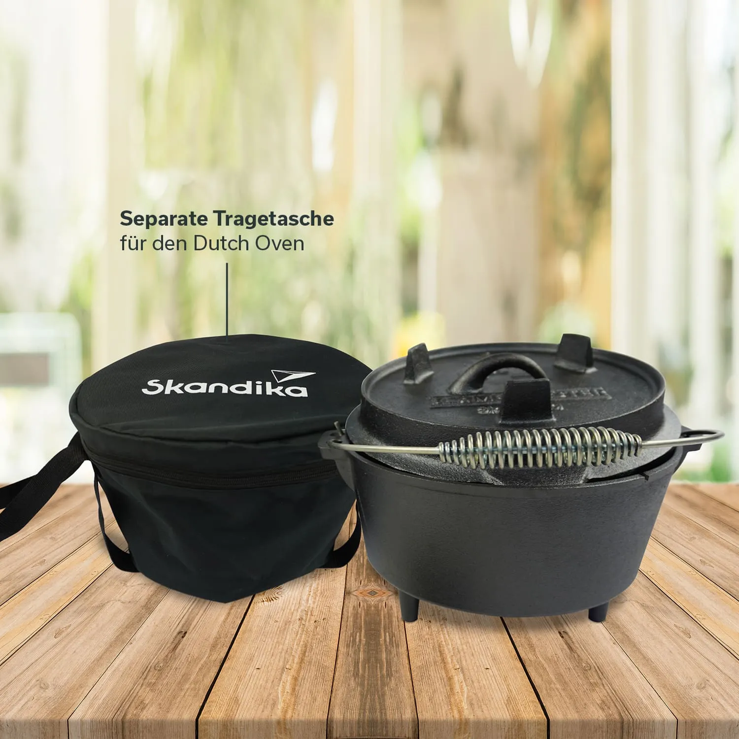 Schwarze Tr Tasche mit Aufschrift "Skandika" links und ein gusseiserner Dutch Oven mit einem Deckel rechts auf Holzuntergrund.