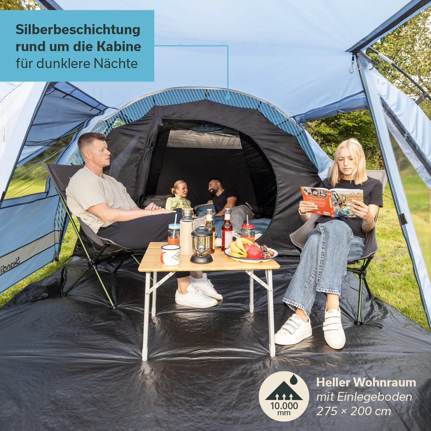 Zelt mit zwei Sitzecken. Eine Person liest, während eine andere mit zwei Kindern spricht. Auf einem Tisch stehen Getränke und Obst.