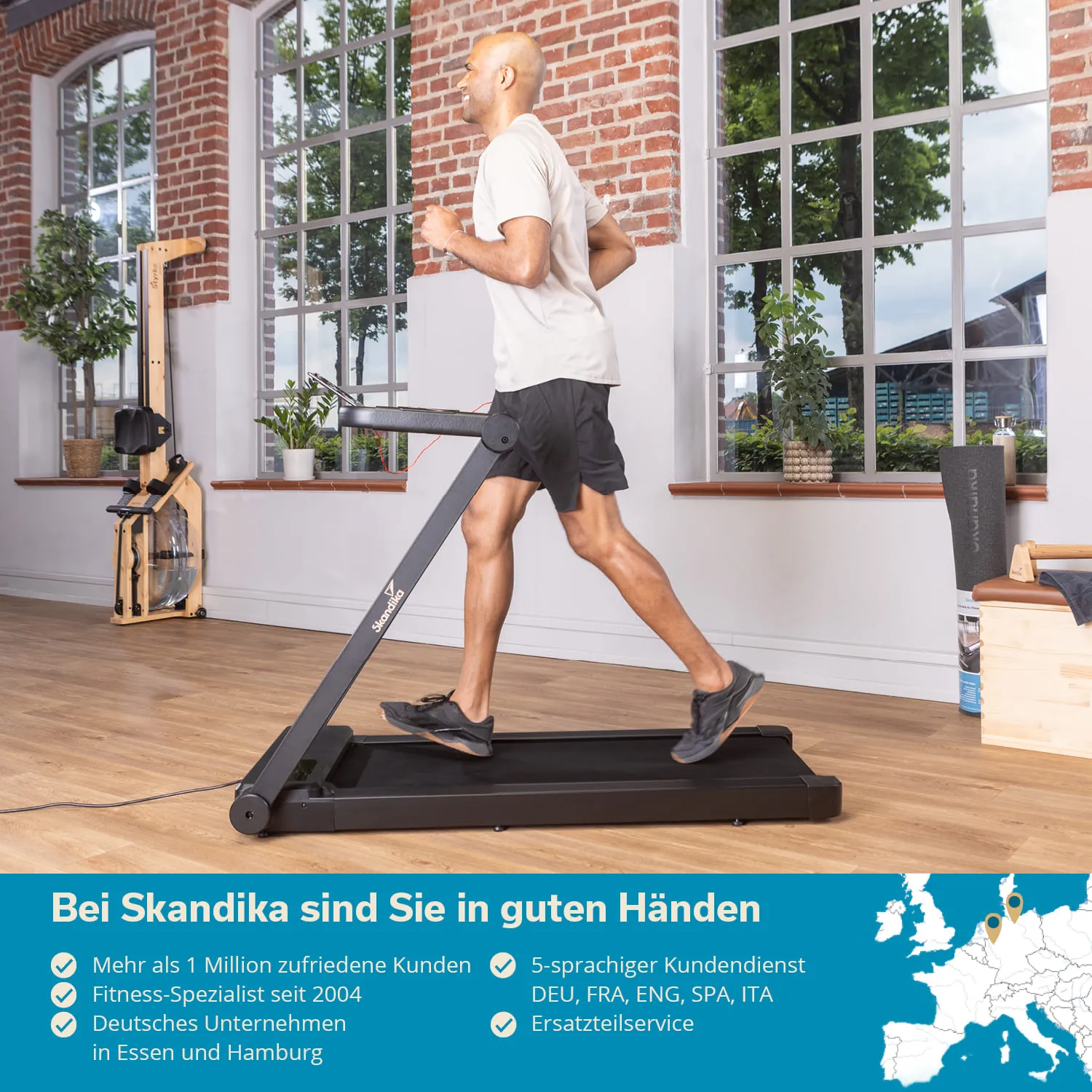 Mann joggt auf einem schwarzen Laufband in einem hellen Raum mit großen Fenstern. Pflanzen und Fitnessgeräte im Hintergrund.