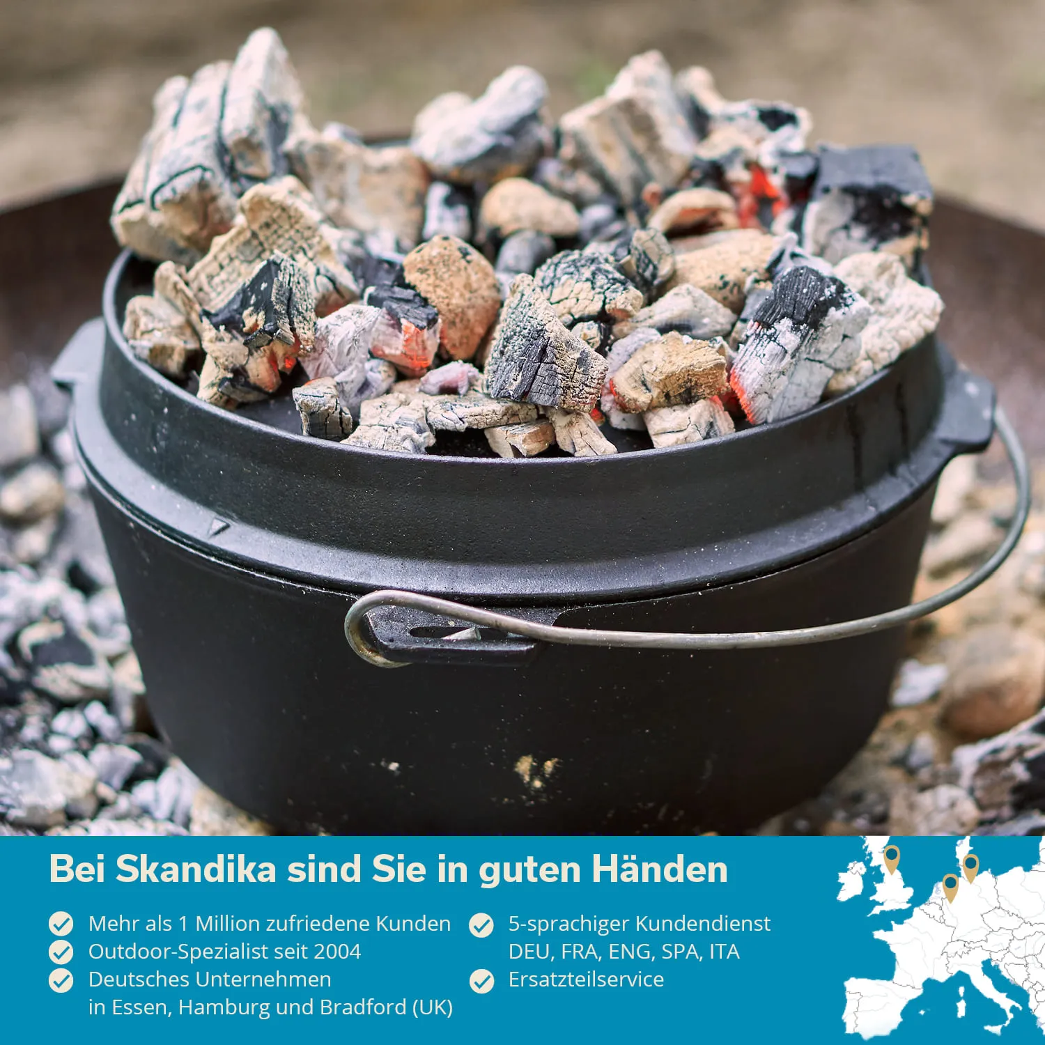 Schwarzer Topf mit glühenden Kohlen, die oben sichtbar sind. Hintergrund unscharf, mit einem grauen Boden.