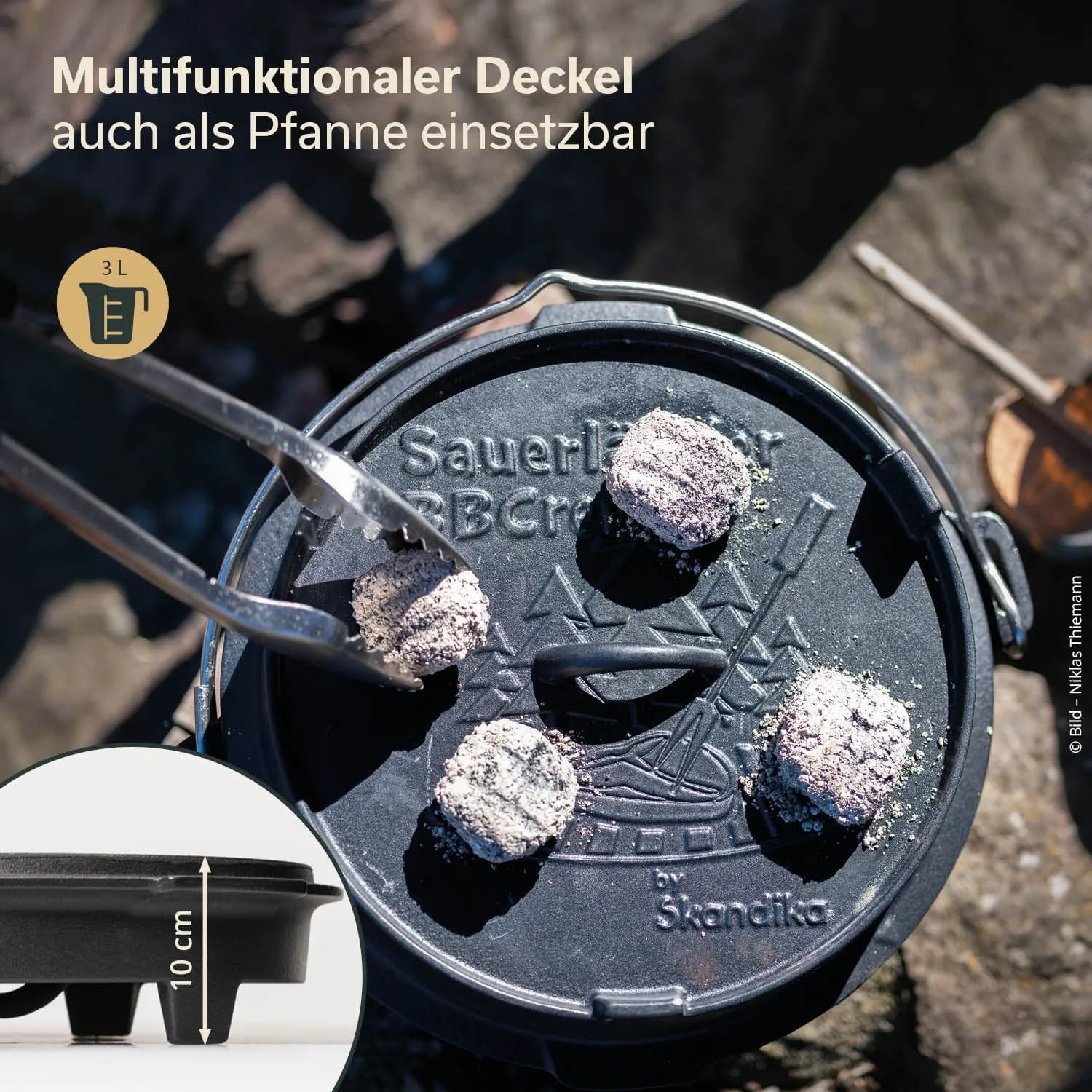 Ein schwarzer, runder Deckel mit einem Griff und mehreren Grillkohle-Stücken darauf, neben einem kleinen, quadratischen Bild mit Maßangabe.