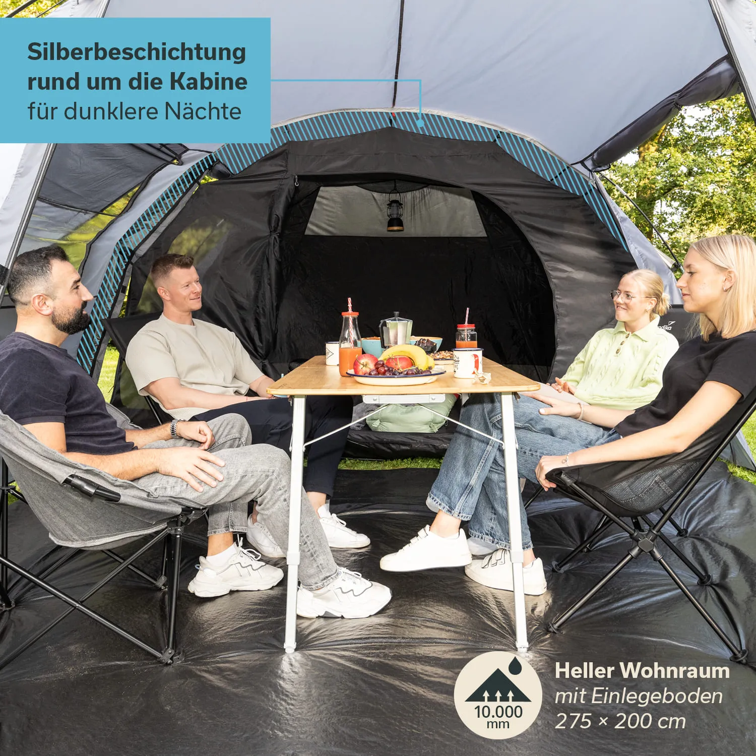 Zeltinnenraum mit vier Personen, die um einen Tisch mit Essen sitzen. Heller Wohnraum, von grauem Zeltstoff umgeben.