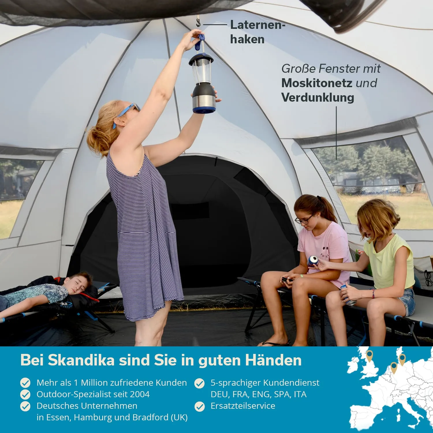 Eine Person hängt eine Laterne in einem Zelt auf. Im Hintergrund sitzen zwei Personen auf Campingsesseln. Das Zelt hat große Fenster mit Moskitonetz.