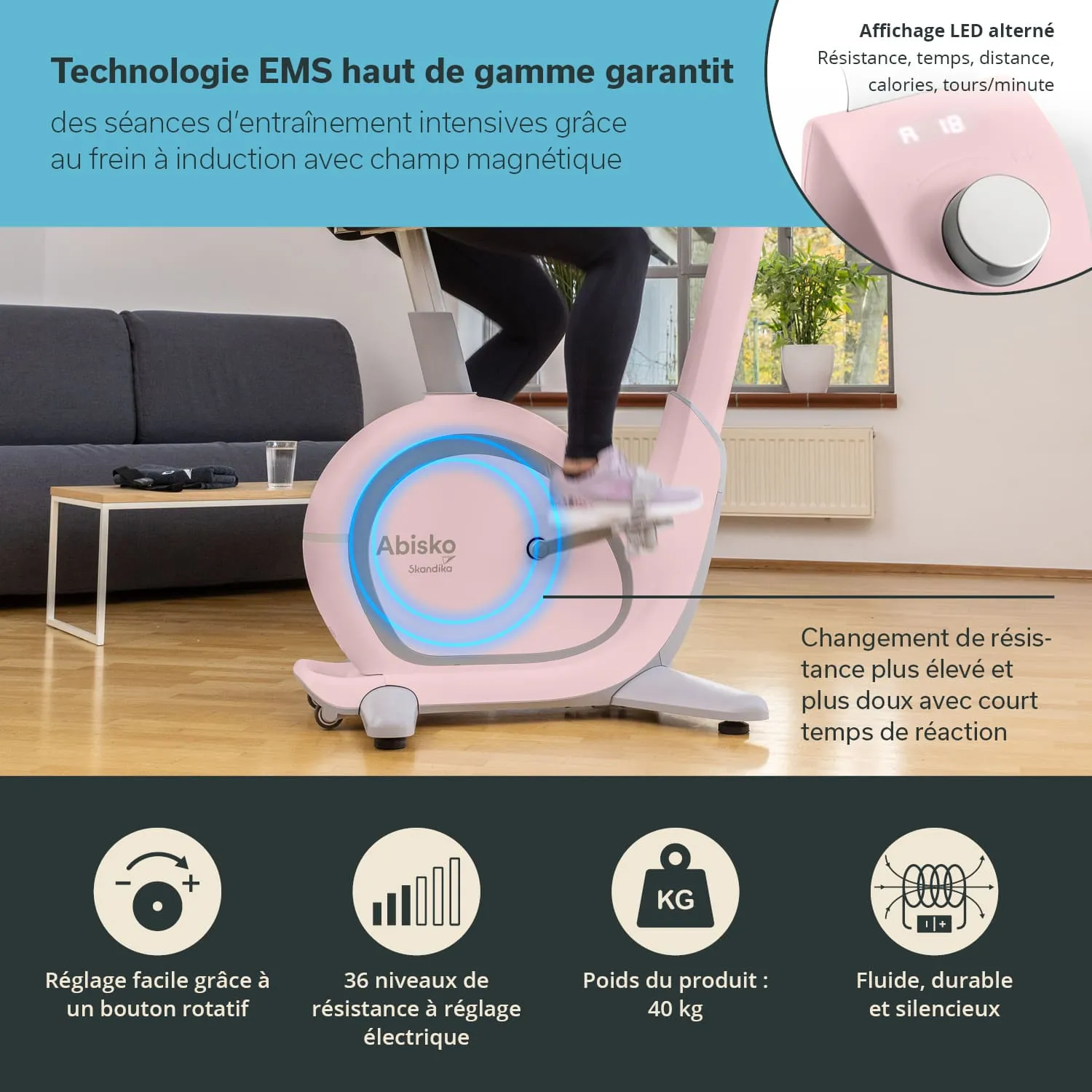 Eine Trainingsgerät, ein Heimtrainer in Rosa, steht in einem hellen Raum. Im Vordergrund ist ein Fuß einer Person sichtbar, die gerade strampelt. Auf dem Gerät gibt es ein LED-Display, das Informationen anzeigt.