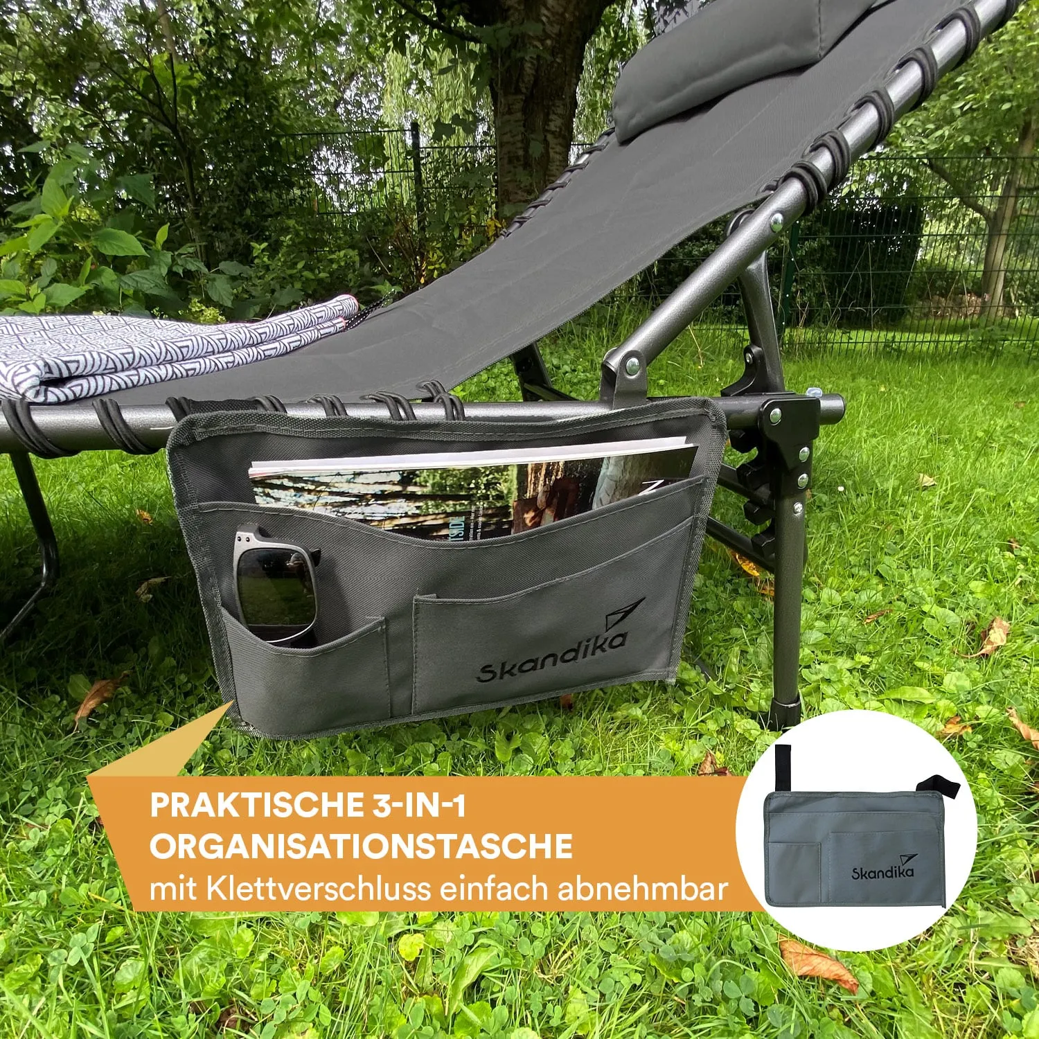 Graue Organisations-Tasche hängt an einem Liegestuhl. Ein Handy und ein Buch sind sichtbar. Im Hintergrund Gras und Bäume.