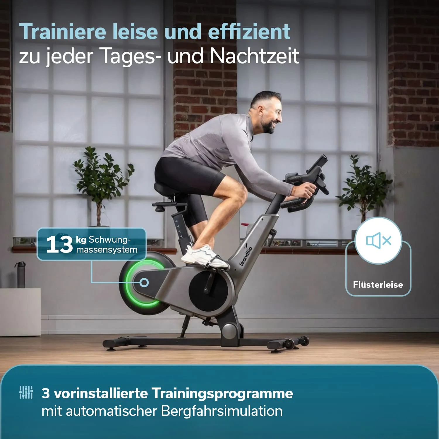 Mann auf einem Trainingsfahrrad in einem hellen Raum mit großen Fenstern und Pflanzen im Hintergrund.