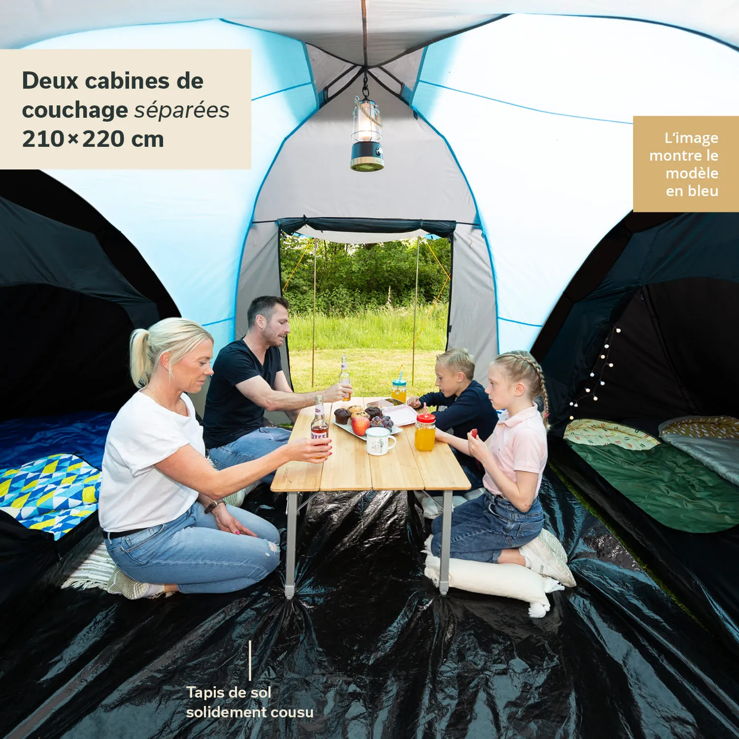 Familie sitzt an einem Tisch im Inneren eines Zeltes. Zwei Kinder und zwei Erwachsene genießen Snacks und Getränke.