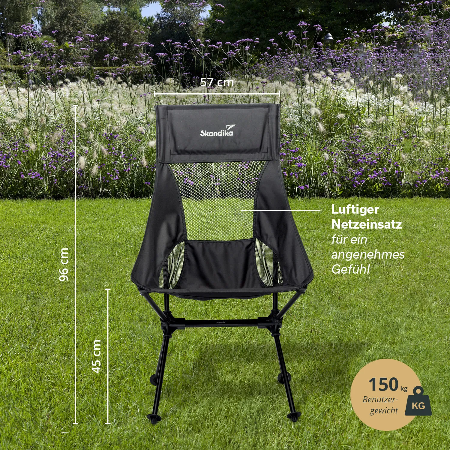 Schwarzer Campingstuhl mit Netzeneinsatz auf grünem Gras, umgeben von lila Blumen. Maße: 96 cm hoch, 57 cm breit, 45 cm Sitzhöhe.