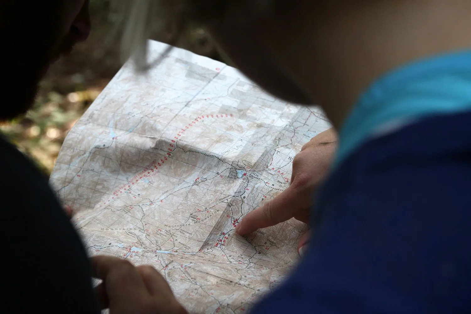 Nahaufnahme einer Wanderkarte mit einer Person, die den Finger auf die Karte zeigt