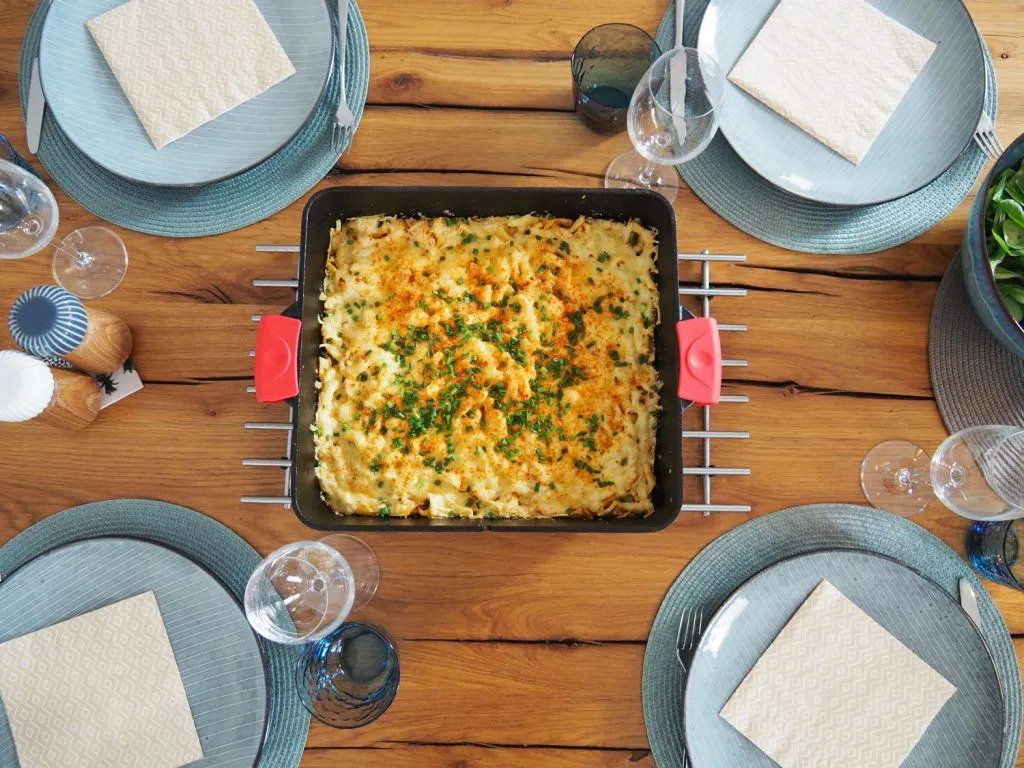 Dutch Oven Käsespätzle serviert auf Tisch mit vier Tellern