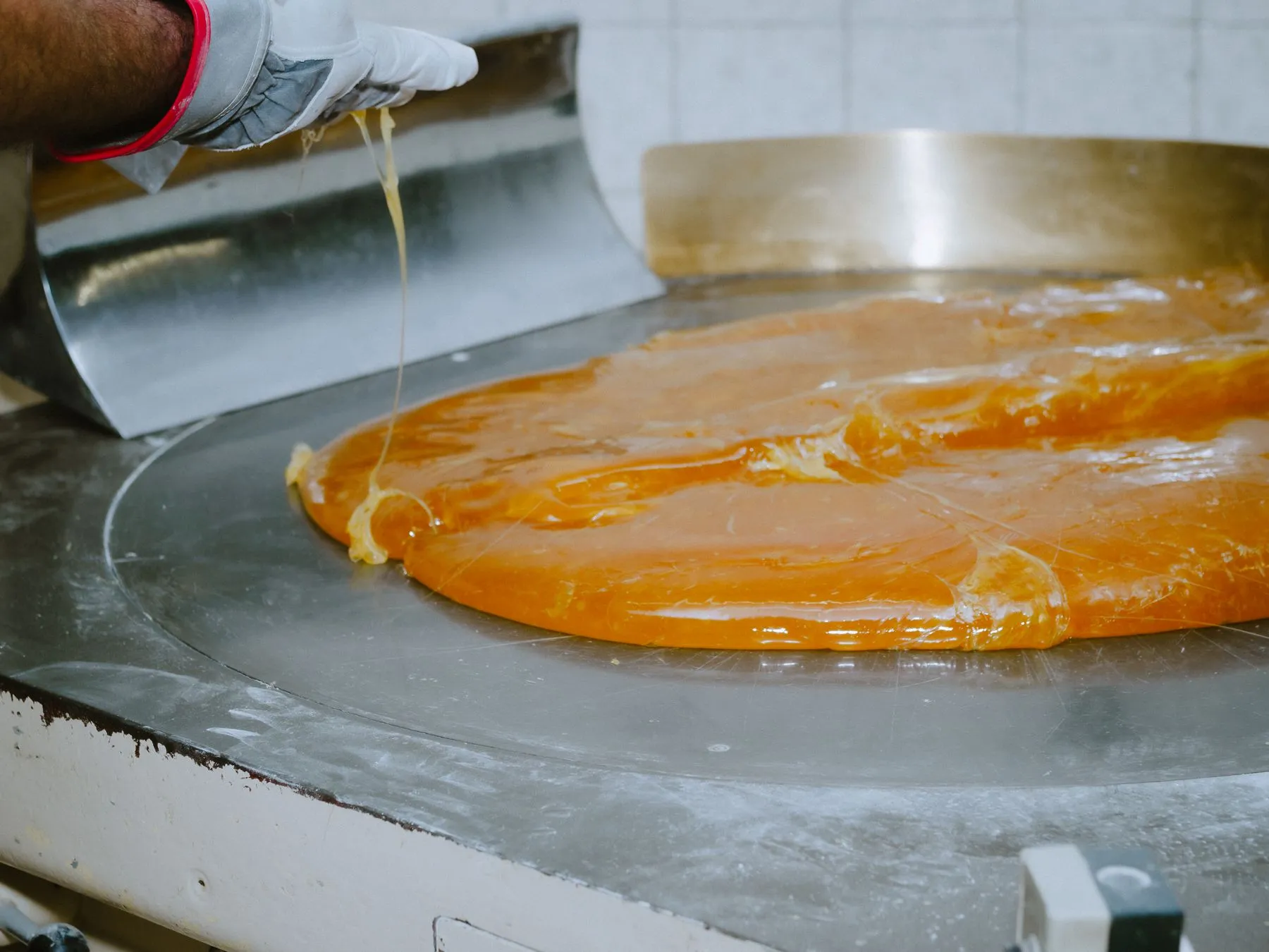 Bonbonmasse wird von Hand auf wassergekühlten Platten mit Schafshandschuhen gezogen