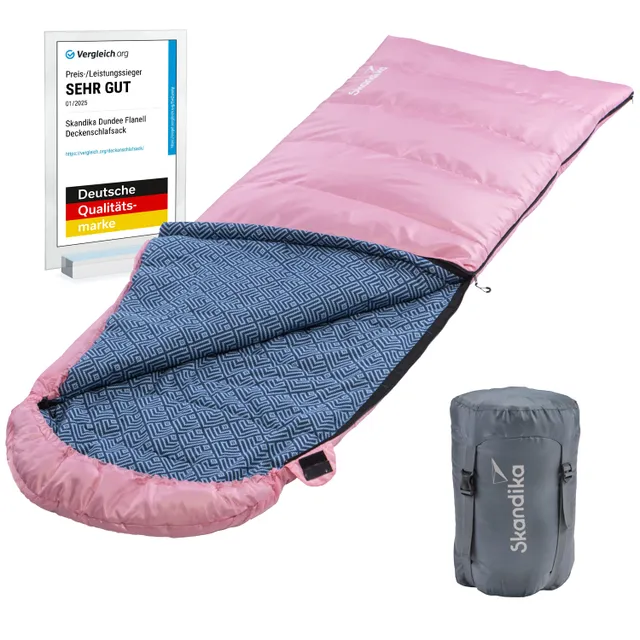 Rosa Decken-Schlafsack mit blauem Innenfutter und geometrischem Muster, daneben eine graue Packtasche und eine Auszeichnung.