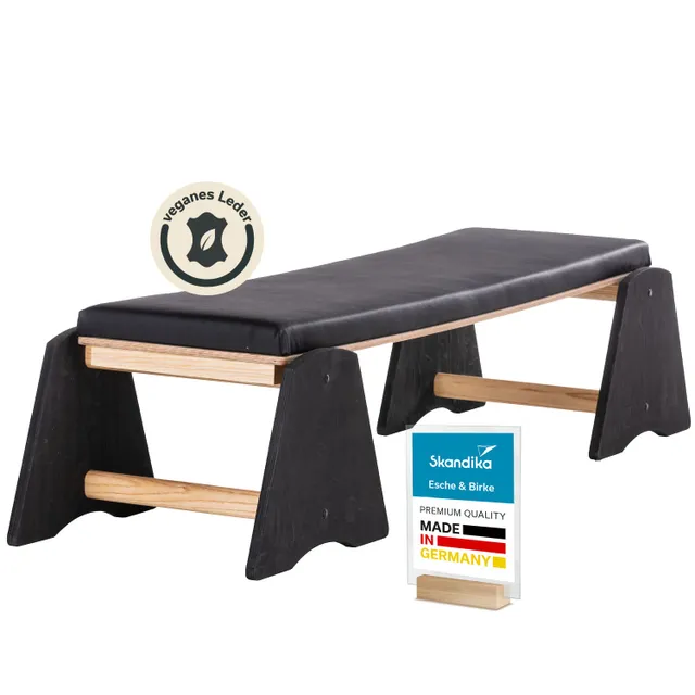 Bank aus Holz mit schwarzer Polsterung. Dazu ein Schild mit Informationen über das Produkt und ein Symbol für veganes Leder.