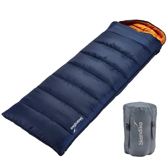 Schlafsack in Blau mit orangefarbenem Innenfutter, daneben grauer Packsack. Beide Gegenstände auf weißem Hintergrund.