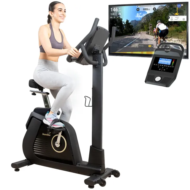 Fitnessbike mit Person in Sportbekleidung. Bildschirm zeigt Radfahrstrecke an. Bedienelemente auf dem Gerät sichtbar.