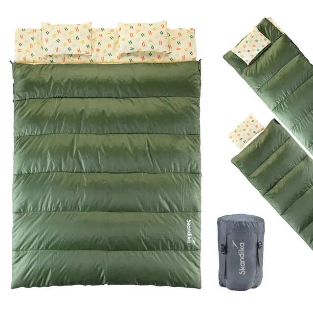 Schlafsack in Dunkelgrün mit zwei Kissen, die ein buntes Muster haben. Eingerollt und in einer Tasche präsentiert.
