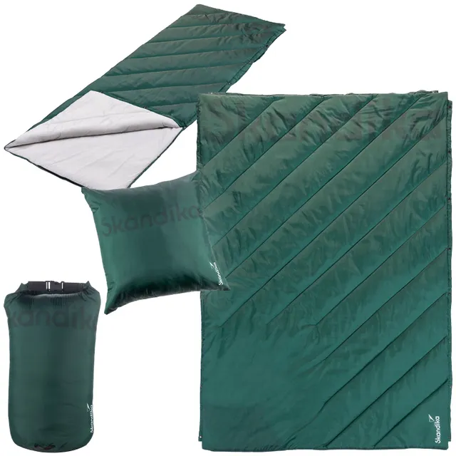 Schlafsack und Kissen in Dunkelgrün, mit diagonalen Steppnähten und einem Kompressionsbeutel.